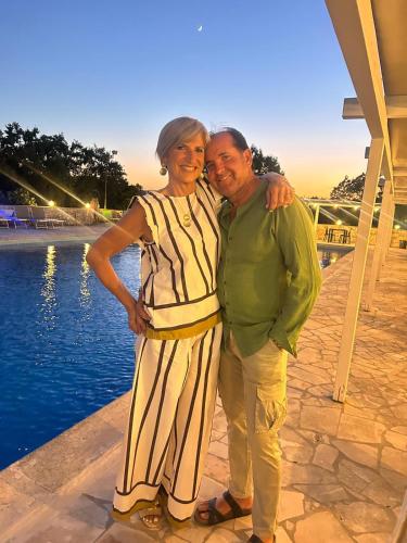 a man and a woman standing next to the water at B&B Luxury Villa Olimpia Home Restaurant in Selva di Fasano