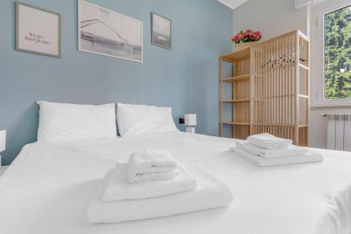 Una cama blanca con toallas encima. en Easy LIN Apartment, en Milán