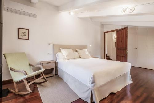 a bedroom with a large white bed and a chair at The Old Cottage - Cas Julians Sencelles Ruberts in Sencelles