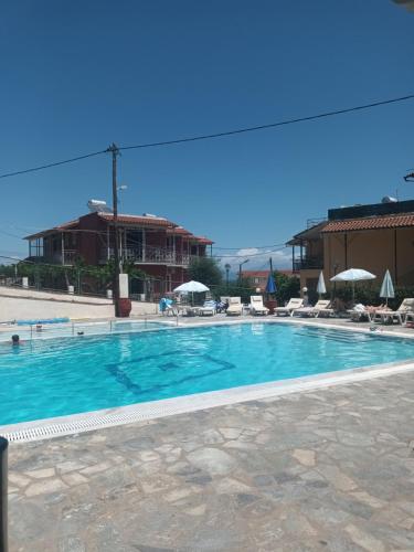 a large swimming pool with chairs and a building at Art Studios Benitses in Benitses