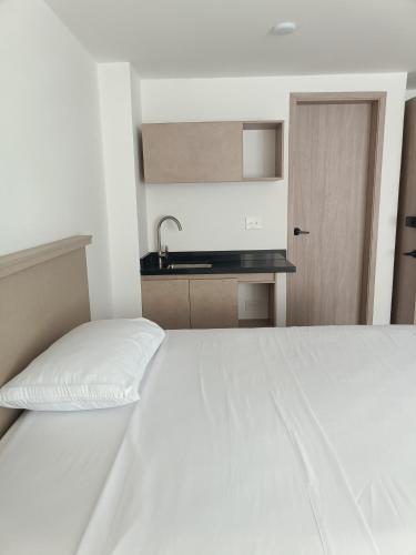 a white bed in a white room with a kitchen at Moderno Apartamento en el Norte de Cali in Cali
