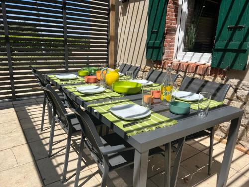 - une table avec des assiettes et des bols sur une terrasse dans l'établissement Jolie Maison avec Balnéothérapie, à Baudrières