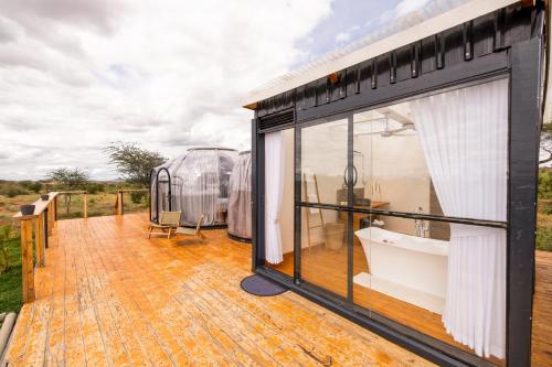 a large glass house on a wooden deck at Nanare Chalets Amboseli in Poka