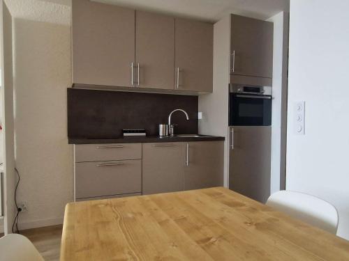 Il comprend une cuisine avec une table en bois et un évier. dans l'établissement Studio cosy pour 4 pers à L'Alpe d'Huez, près des pistes, animaux bienvenus - FR-1-405-14, à L'Alpe-d'Huez