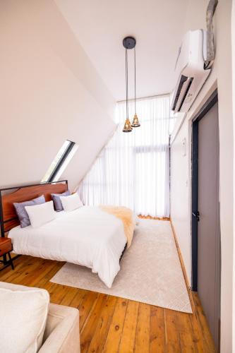 a bedroom with a bed with white sheets and wood floors at Nanare Chalets Amboseli in Poka