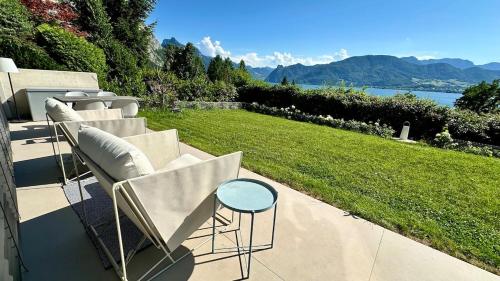 a patio with chairs and a table and a lawn at Traumsee Lodge am Traunsee in Gmunden mit 180 Grad See- und Traunsteinblick in Gmunden