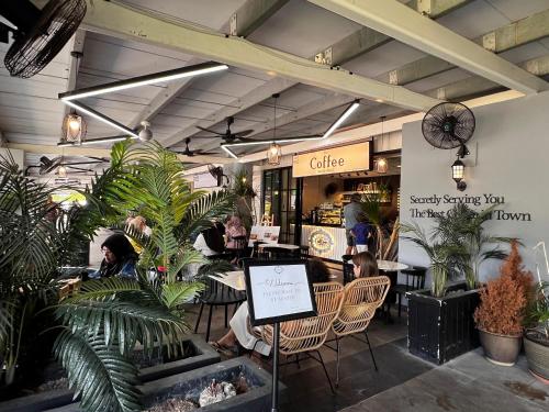ein Restaurant mit Leuten, die an Tischen und Pflanzen sitzen in der Unterkunft CasaZlyn Studio By MySky Stays at Presint 5, Putrajaya in Putrajaya