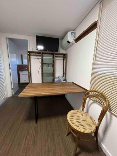 a room with a wooden table and a chair at Flat dos Amigos na Villela Home Stay - DF in Brasilia