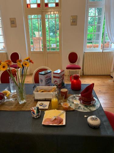 une table noire avec de la nourriture dessus avec des chaises rouges dans l'établissement Manoir de la Gravette, Maison & Table d'Hôtes, à Montauban