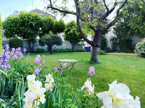 a table in the middle of a garden with flowers at La Métairie in Vernou-sur-Brenne