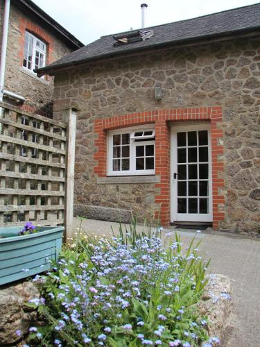 a stone house with a window and flowers in front of it at Budleigh Farm Cottages in Moretonhampstead