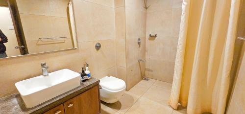 a bathroom with a sink and a toilet and a mirror at Hotel Nova Viva in Rajkot