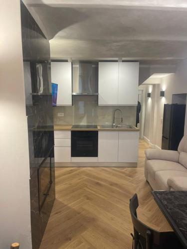 a kitchen with white cabinets and a living room at Maison Simo in Pescasseroli