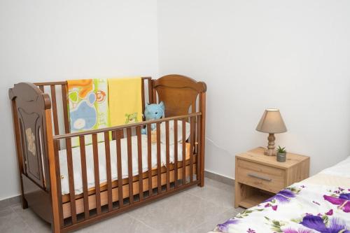 a crib in a bedroom with a bed and a nightstand at F & A Family Home in Zarós