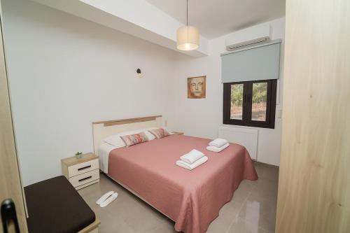 a bedroom with a bed with pink sheets and a window at F & A Family Home in Zarós