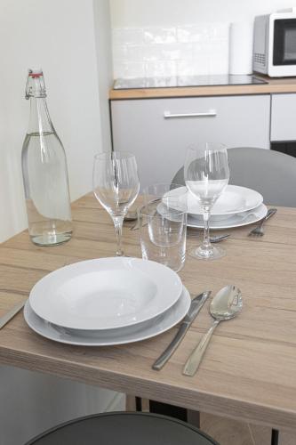 - une table avec des assiettes blanches et des verres à vin dans l'établissement La Belle Endormie - Centre Ville - Elégant, à Bordeaux