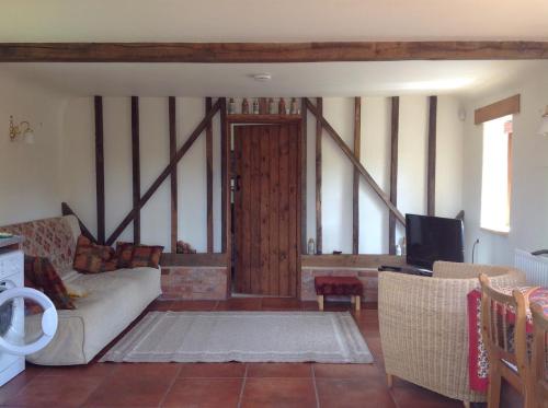 a living room with a couch and a tv at Hops and the Vines in Shipston on Stour