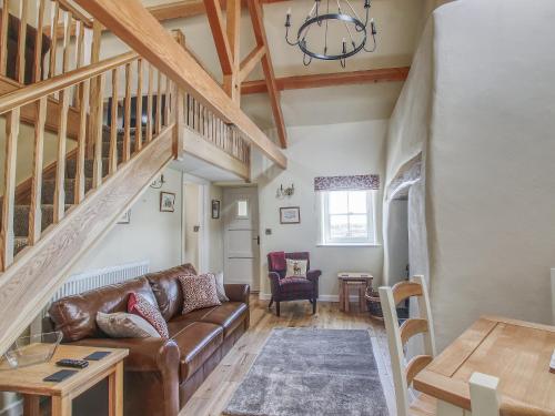 sala de estar con sofá de cuero marrón y escaleras en Fferam Gorniog, en Holyhead