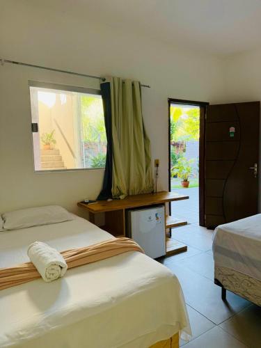 a hotel room with two beds and a window at Pousada Palmeiras in Santo Amaro