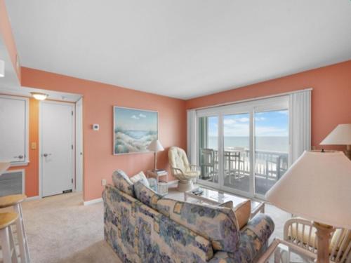 a living room with a couch and a large window at Ocean Breeze - Stunning Views - Oceanfront - 3rd floor - You deserve a beach vacation! condo in Carolina Beach