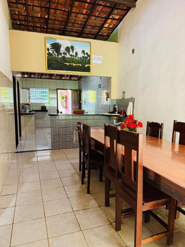 a dining room with a table and chairs and a kitchen at Pousada Palmeiras in Santo Amaro