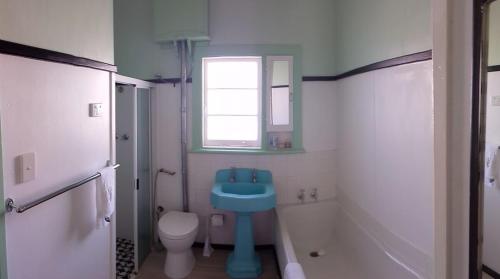 bagno con lavandino blu e servizi igienici di Albert Road Cottage - late art deco 3 bedroom house and caravan a Bunbury