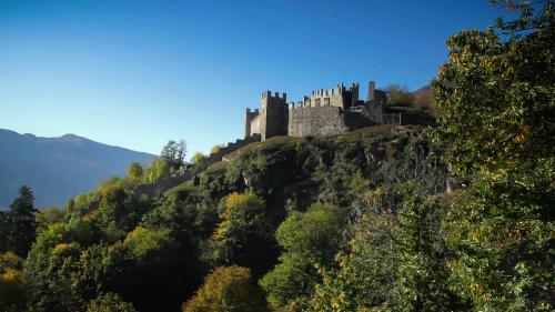 a castle on top of a hill with trees at Romantico - SAUNA- il tuo week end di coppia in Valtellina- in Grosio