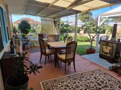 un patio con tavolo, sedie e un divano di Albert Road Cottage - late art deco 3 bedroom house and caravan a Bunbury