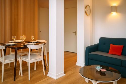 a living room with a table and a blue couch at L'Oasis Sauvage in Wimereux
