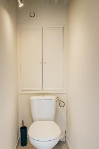 a bathroom with a toilet with a cabinet above it at L'Oasis Sauvage in Wimereux