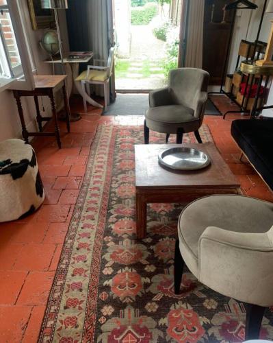 a living room with chairs and a table and a rug at Le petit Chapitre in Pinterville