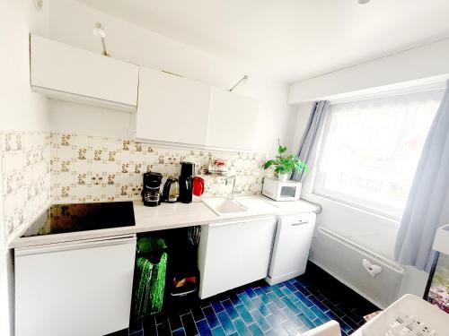 Il comprend une cuisine avec des placards blancs et du carrelage bleu. dans l'établissement Chambre chez l'habitant en hyper centre à Strasbourg, à Strasbourg