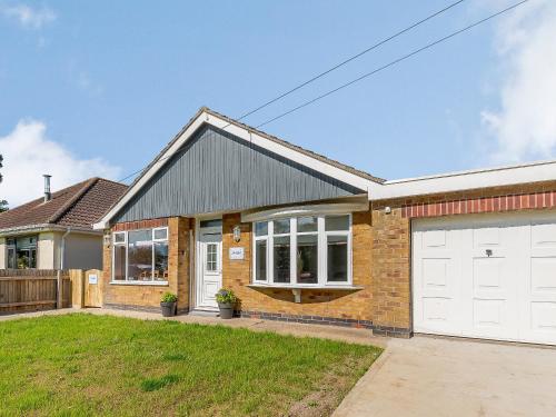 une maison en briques avec des portes de garage blanches dans l'établissement Harebell Cottage, à Addlethorpe