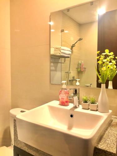 a bathroom with a white sink and a mirror at Uptown Parksuites BGC with Balcony in Manila