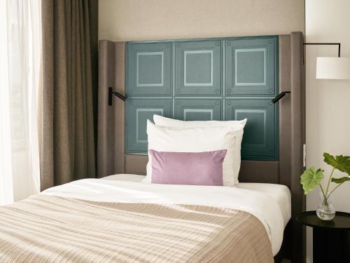 a bed with a blue headboard and a purple pillow at Numa Hamburg Fore in Hamburg