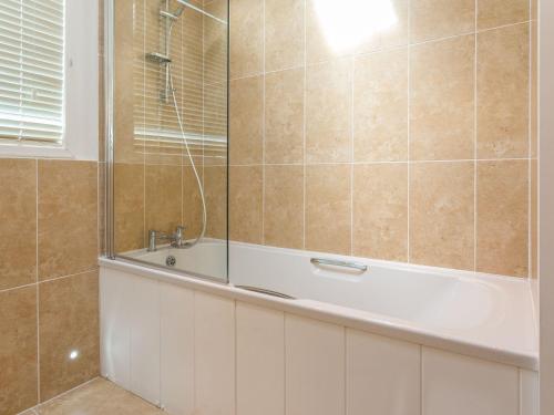 a bathroom with a bath tub and a sink at 2 Tree Tops in Looe