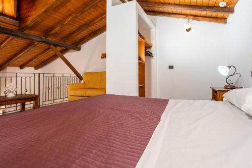 a bedroom with a large bed and a yellow chair at Agriturismo Terrenia in Taormina