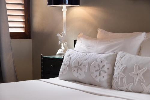 a bed with white pillows and a table with a lamp at Treasure By The Sea Bonaire in Kralendijk