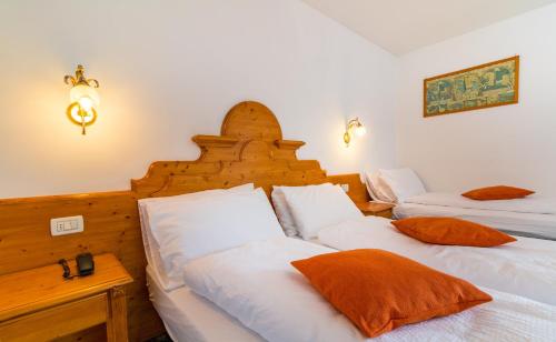 a bedroom with two beds and a wooden headboard at Hotel Bonapace ***S in Madonna di Campiglio