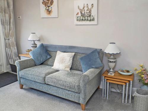 ein Wohnzimmer mit einem grauen Sofa und zwei blauen Kissen in der Unterkunft Comfy Kozy Cottage in Louth