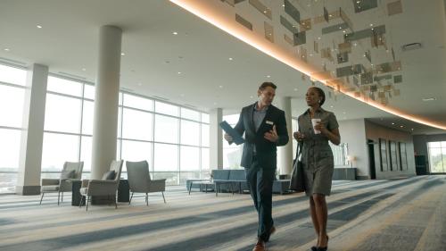 two men walking in an office lobby with their cell phones at Loews Kansas City in Kansas City