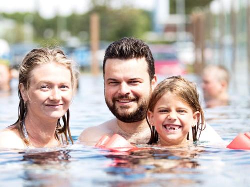 a man and woman swimming in a swimming pool at 4 star holiday home in Nørre Nebel in Nørre Nebel