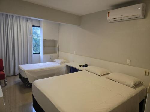 a hotel room with two beds and a window at Apartamento econômico Garvey Hotel in Brasilia