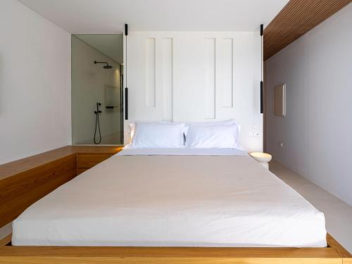 a large white bed in a room with a mirror at Acrodise Estate in Santorini