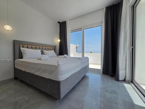 a bedroom with a large bed and a large window at Punta Mare Hotel in Karpathos Town