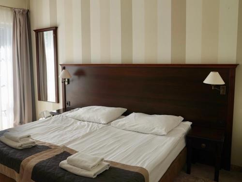 a bedroom with a large bed with two towels on it at Hotel Biały Dwór in Okuninka