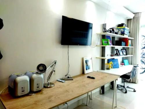 a room with a wooden desk with a television on a wall at Casa Modernista - Aluguel de Suítes in Brasilia