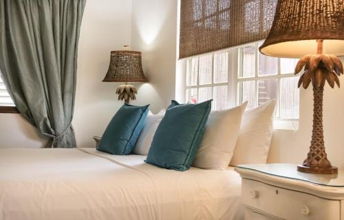 a bedroom with a bed with blue pillows and a window at Treasure By The Sea Bonaire in Kralendijk
