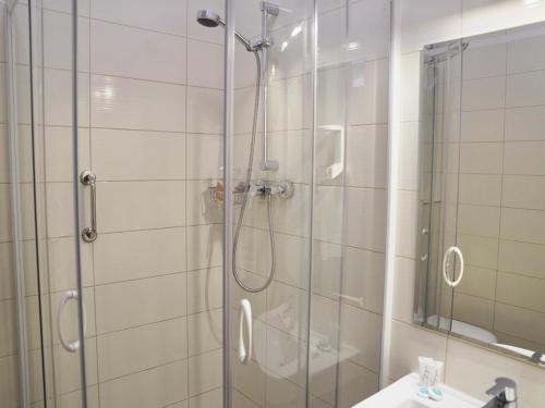 a shower with a glass door next to a sink and a mirror at Hotel Biały Dwór in Okuninka