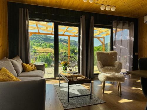 a living room with a couch and a chair and large windows at Varadeo Hill Resort in Şuncuiuş